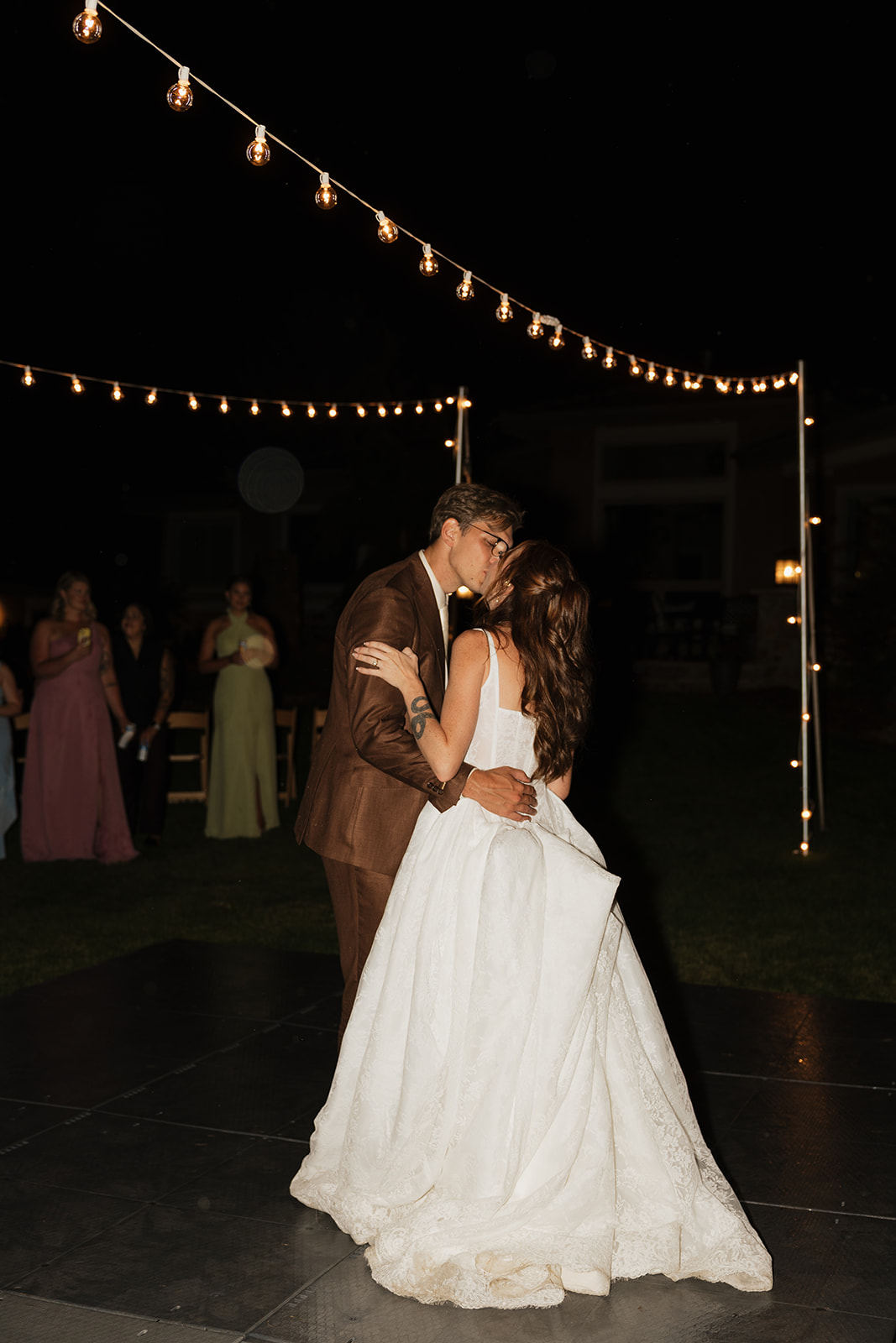 Bride and groom sharing a kiss during their first dance at night
