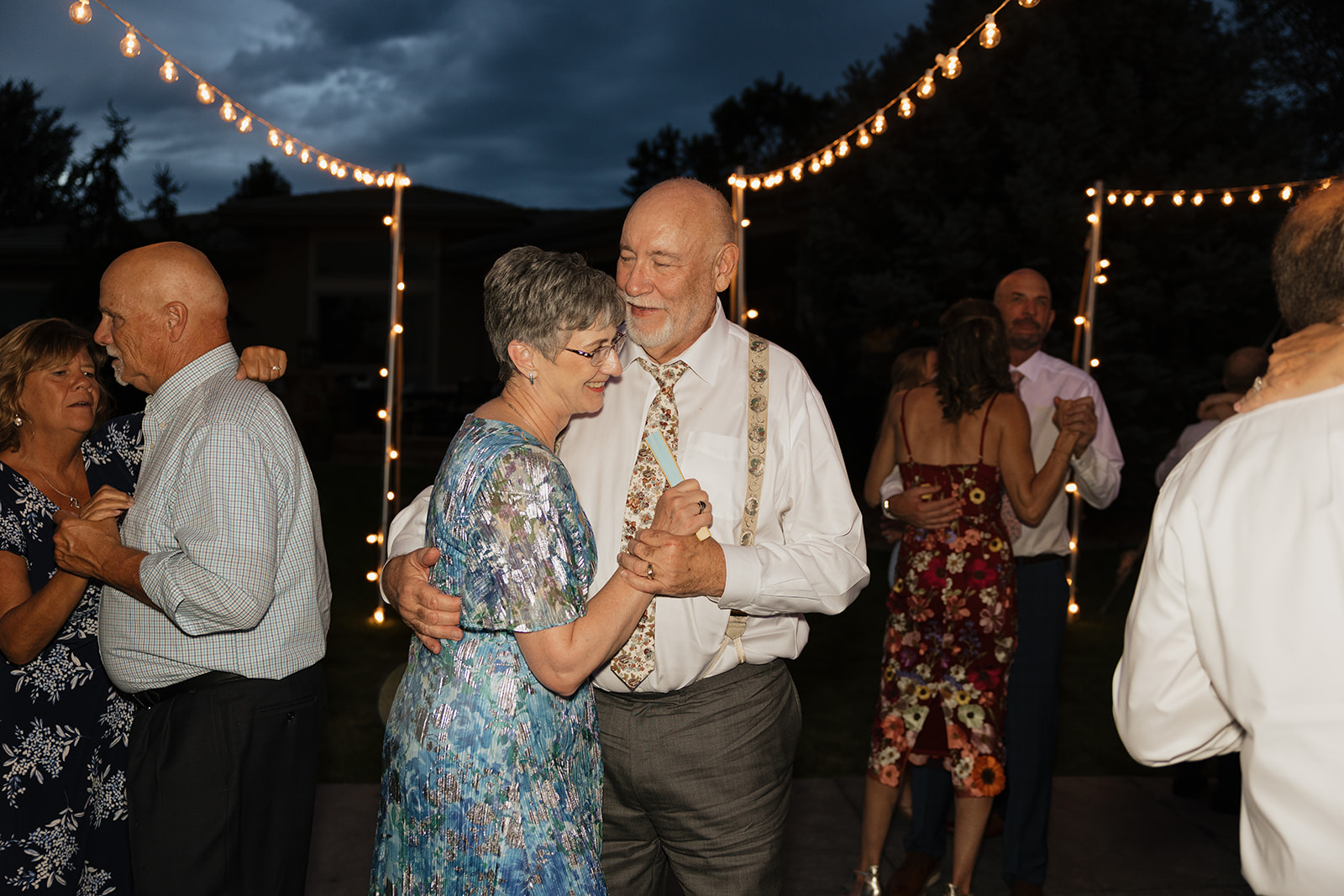 Guests dancing under string lights at an evening backyard wedding