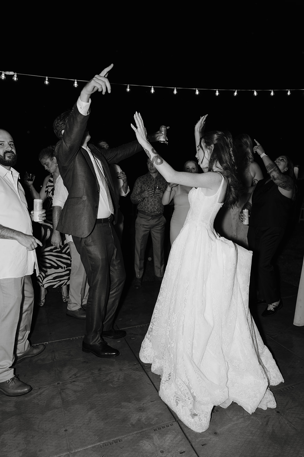 Black and white photo of guests dancing at a nighttime wedding reception
